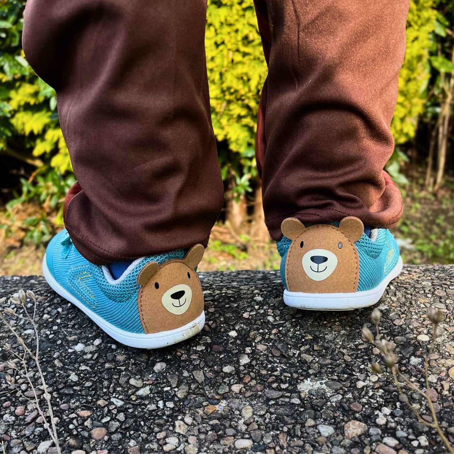 Toddler wearing teal barefoot trainers standing on wall close up