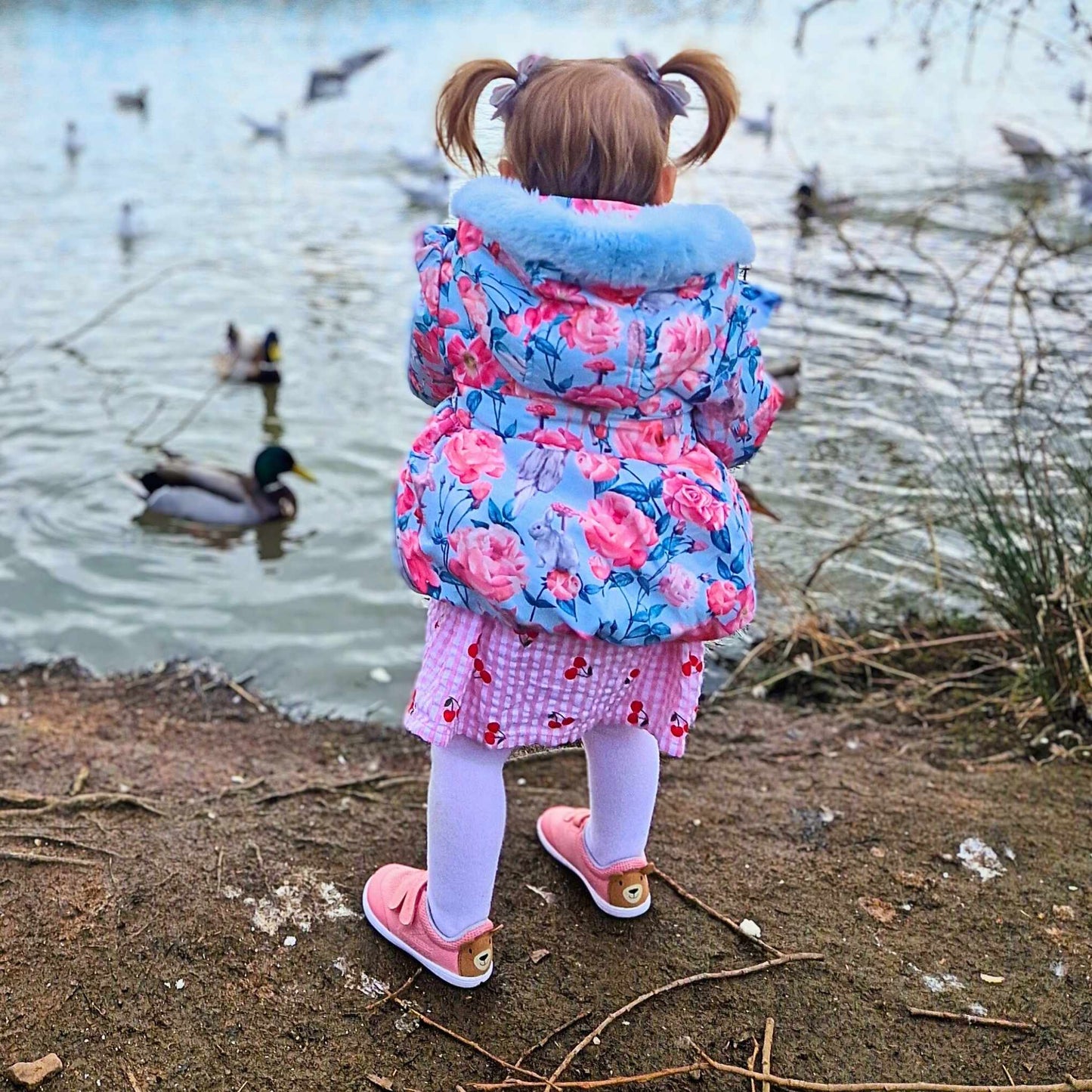 girl toddler wearing pink barefoot trainers near the lake