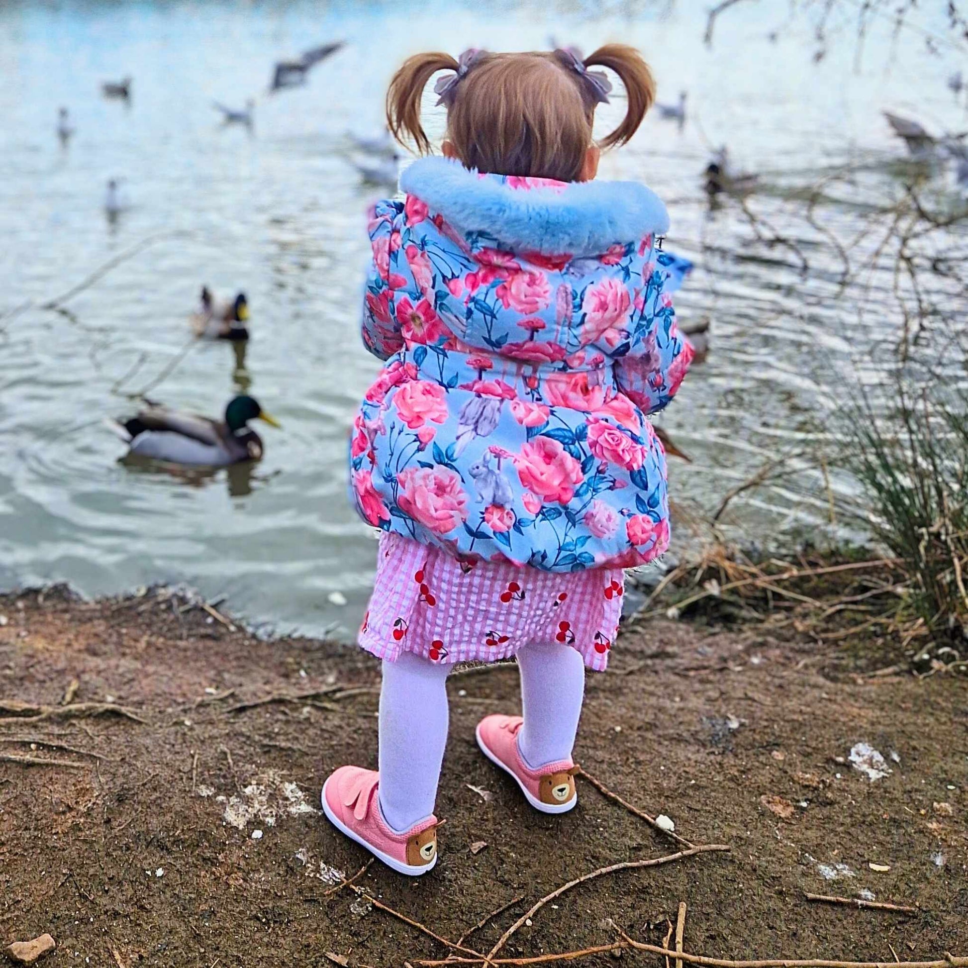 girl toddler wearing pink barefoot trainers near the lake