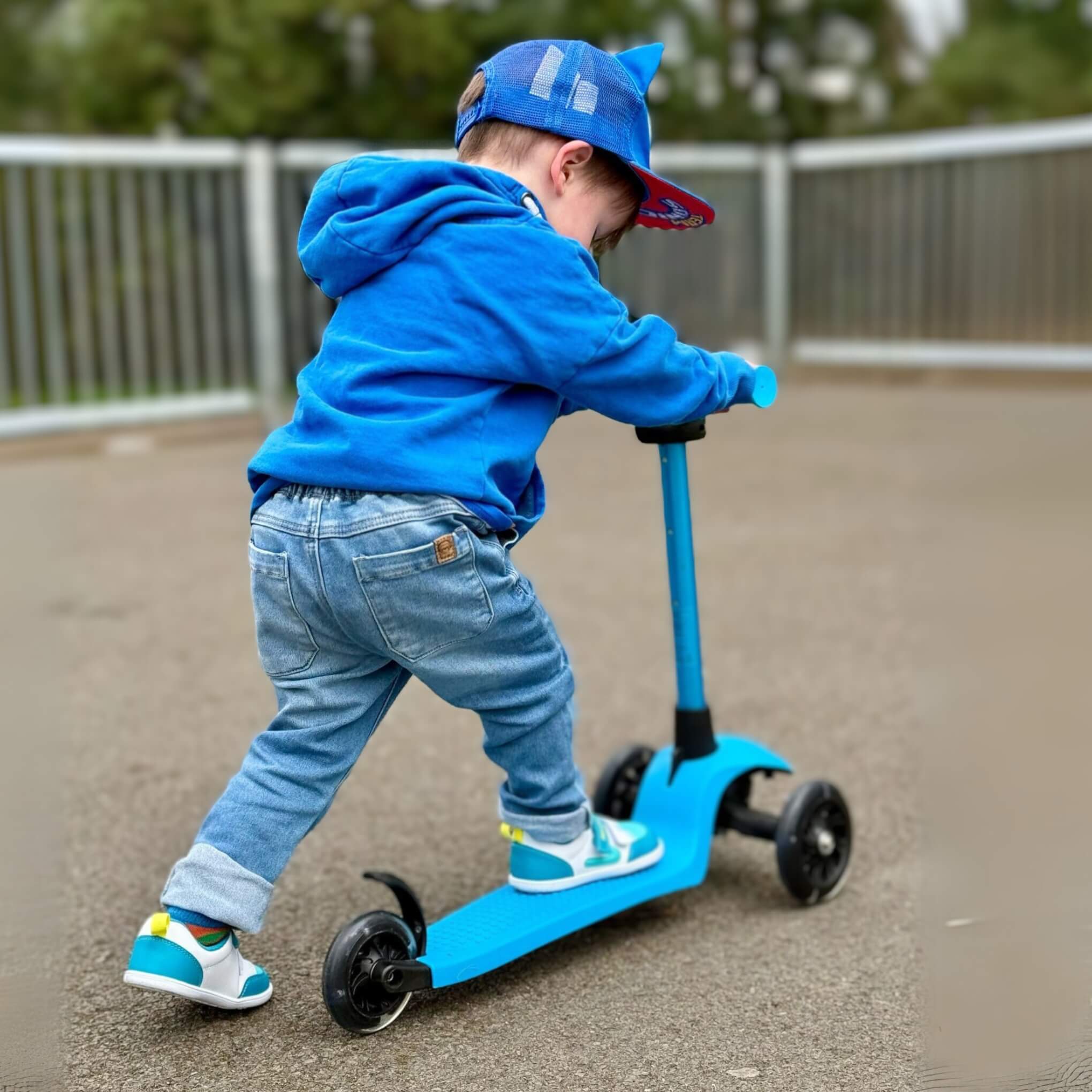 Toddler on scooter in park wearing teal trainers