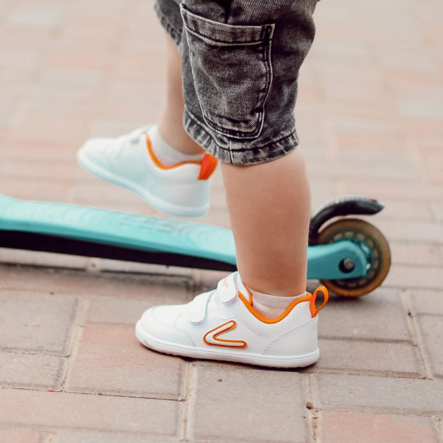 Close up of boy wearing white barefoot trainers on scooter