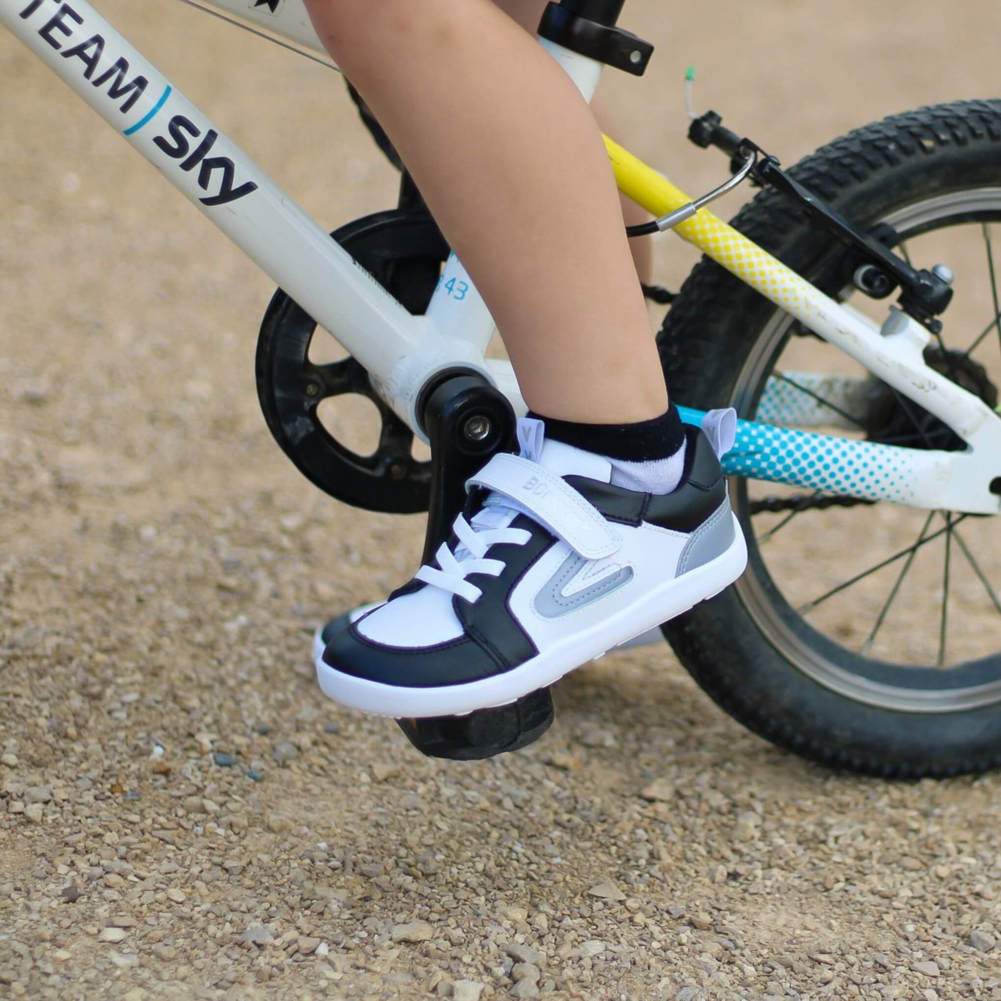 Child's foot wearing a black and white shoe on a bicycle