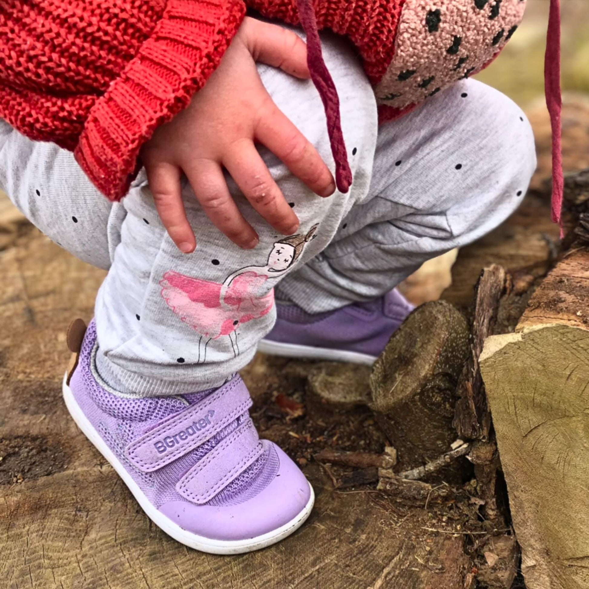 Kid wearing lilac barefoot trainers climbing outdoors.