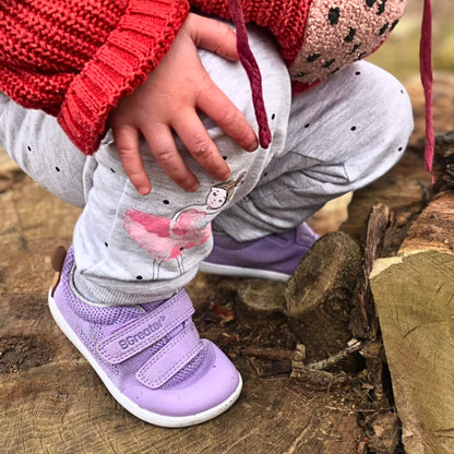 Kid wearing lilac barefoot trainers climbing outdoors.