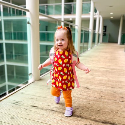 Kid wearing lilac barefoot trainers with hook-and-loop straps walking down an indoor wooden corridor.