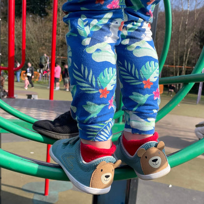 Kid wearing teal barefoot trainers at an outdoor playground.