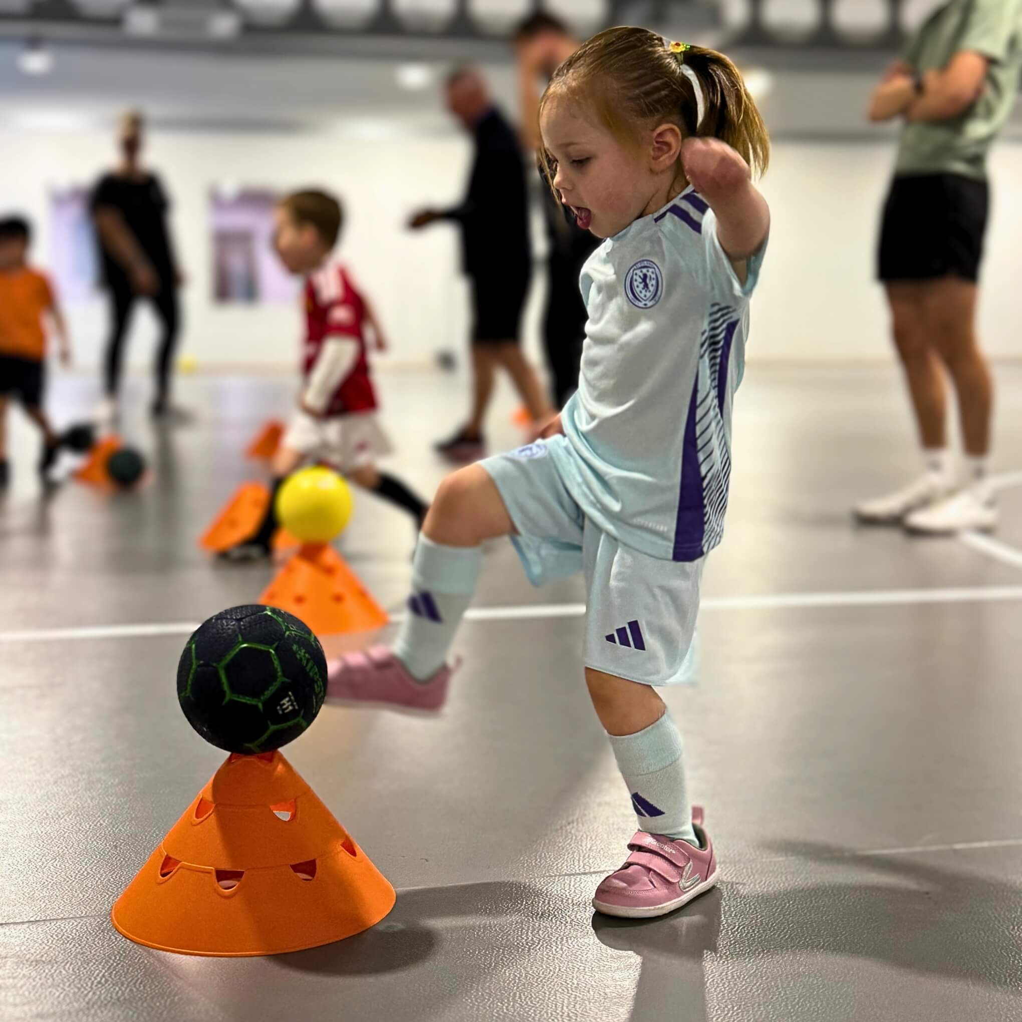 Girl playing football in pink barefoot trainers