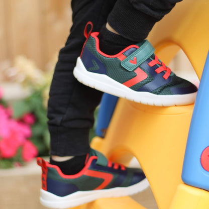 Kid's green, navy and red barefoot trainers on an outdoor climbing frame ladder.