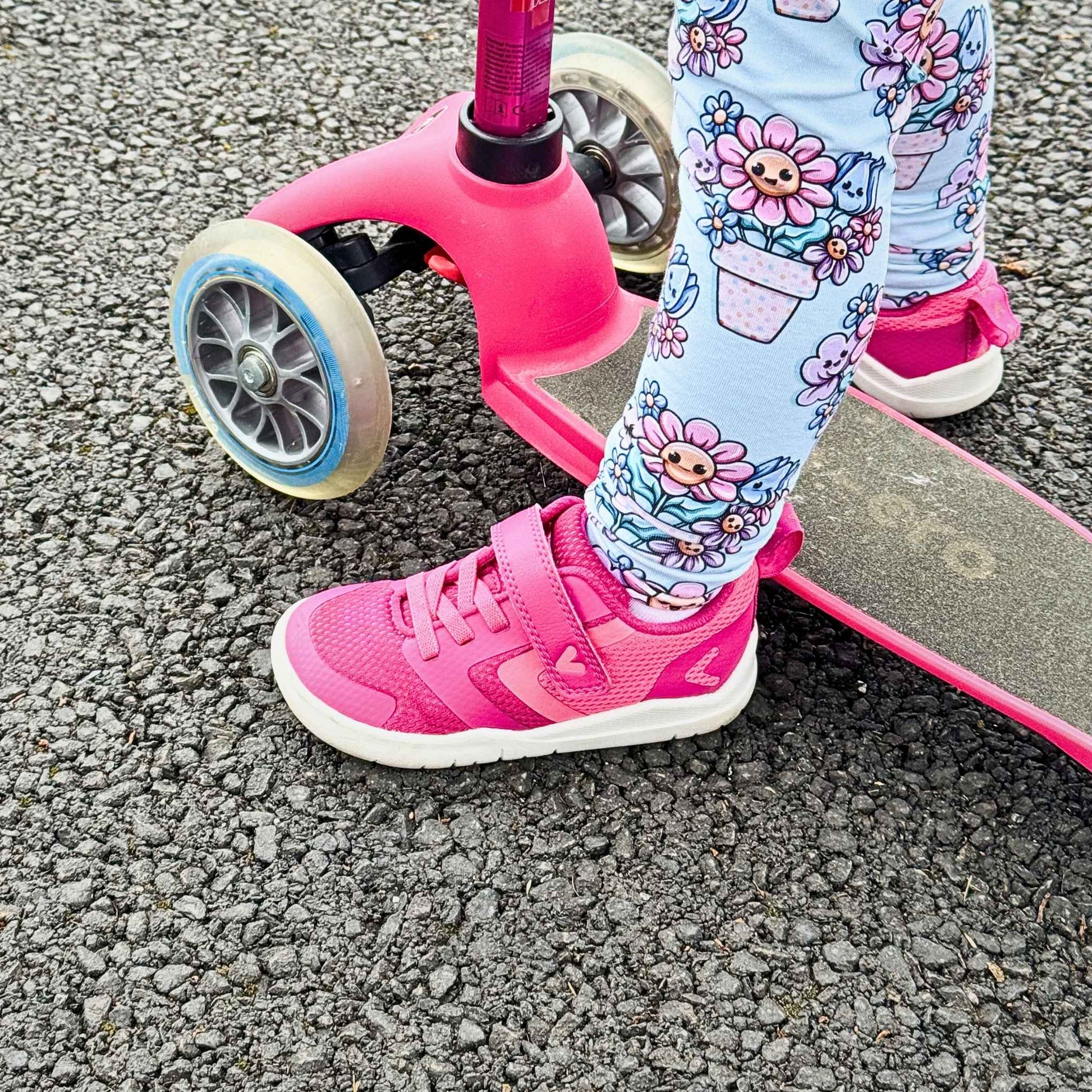 Kids wearing pink barefoot trainers on pink scooter