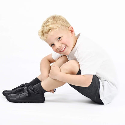 Child wearing black shoes and socks sitting on a white background