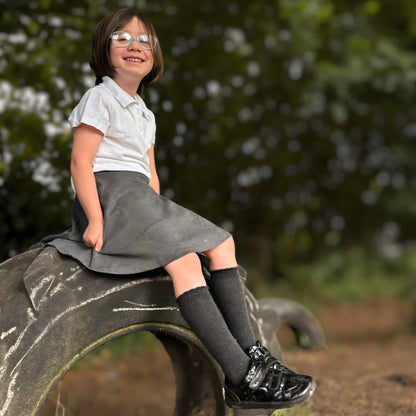 Girl sitting on tyre wearing closed girls school shoes in forest