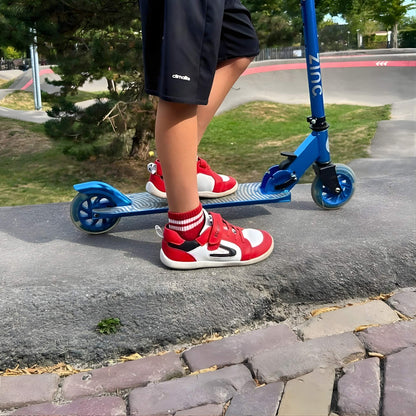 Boy wearing red barefoot trainers on scooter