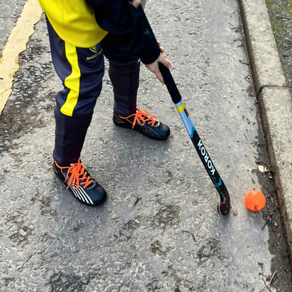 Boy holding a hockey stick in black barefoot trainers