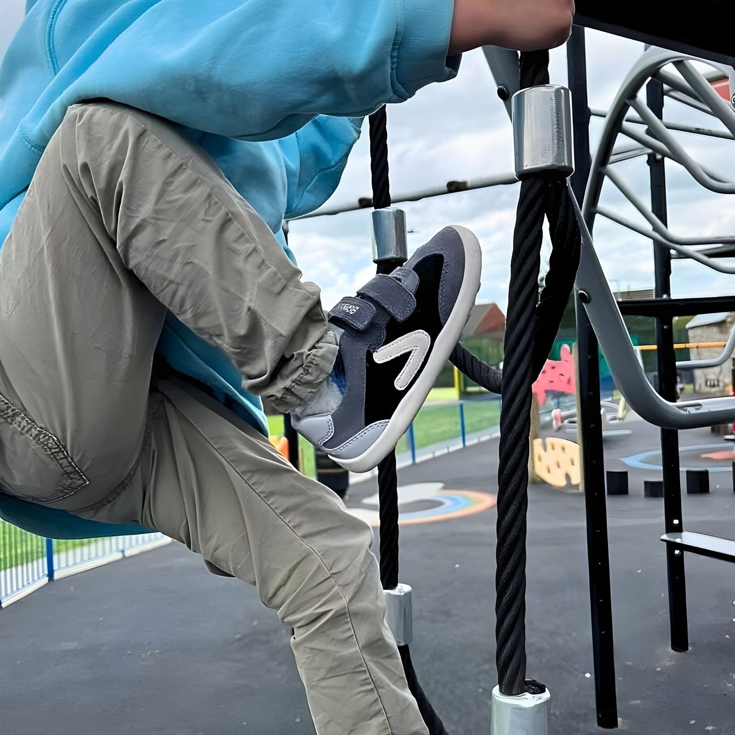 Boy wearing grey black trainers climbing